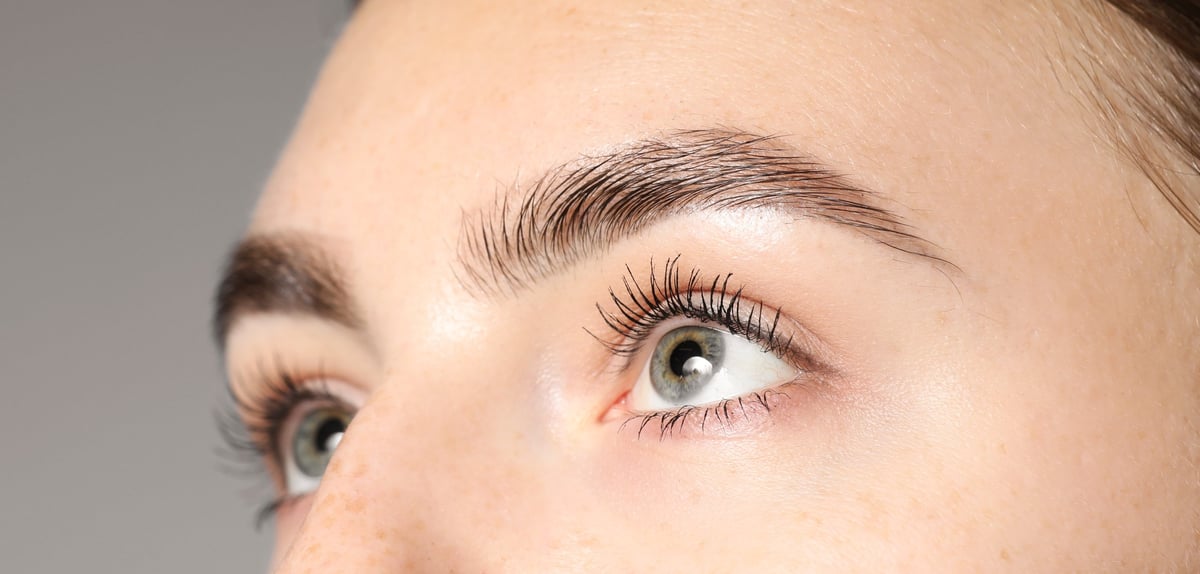 Woman with beautiful eyes and lashes on light grey background