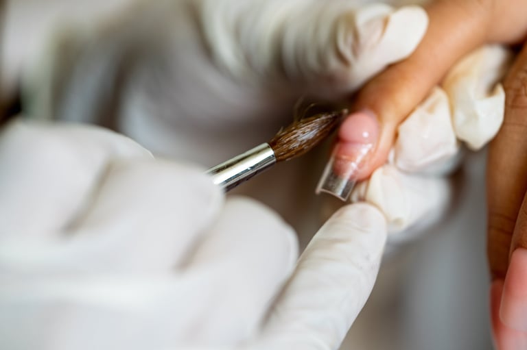 Professional manicurist applying clear acrylic extensions and pink gel to a client's fingernail in a beauty salon