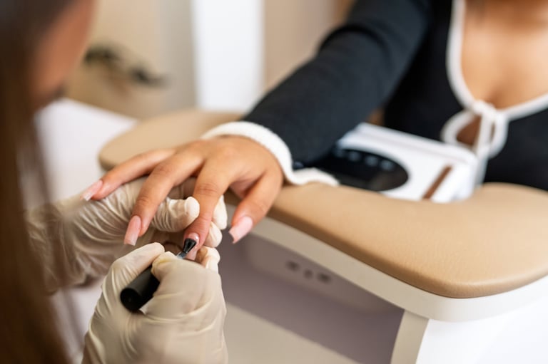 Manicurist wearing gloves carefully applies nail polish to a client's hand